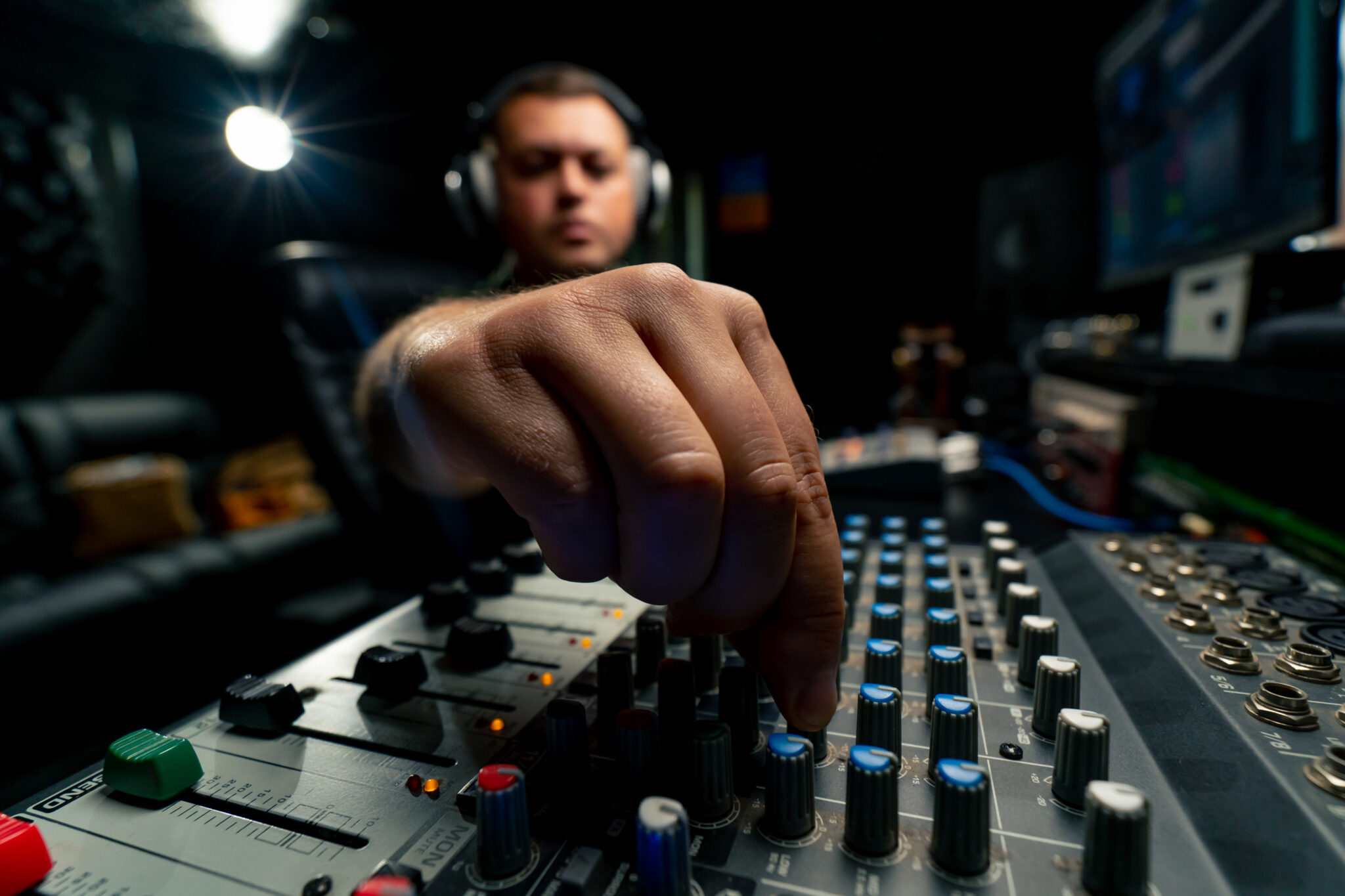 Concentrated male sound engineer working at the mixing console in a music studio to record a soundtrack